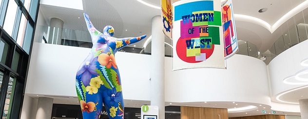 Sculpture of a woman next to a sign with the words Women of the West