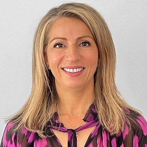 Tina Skliros, Executive Director of Public Private Partnerships at the Victorian Health Building Authority (VHBA). Tina is smiling at the camera and wearing a colourful top