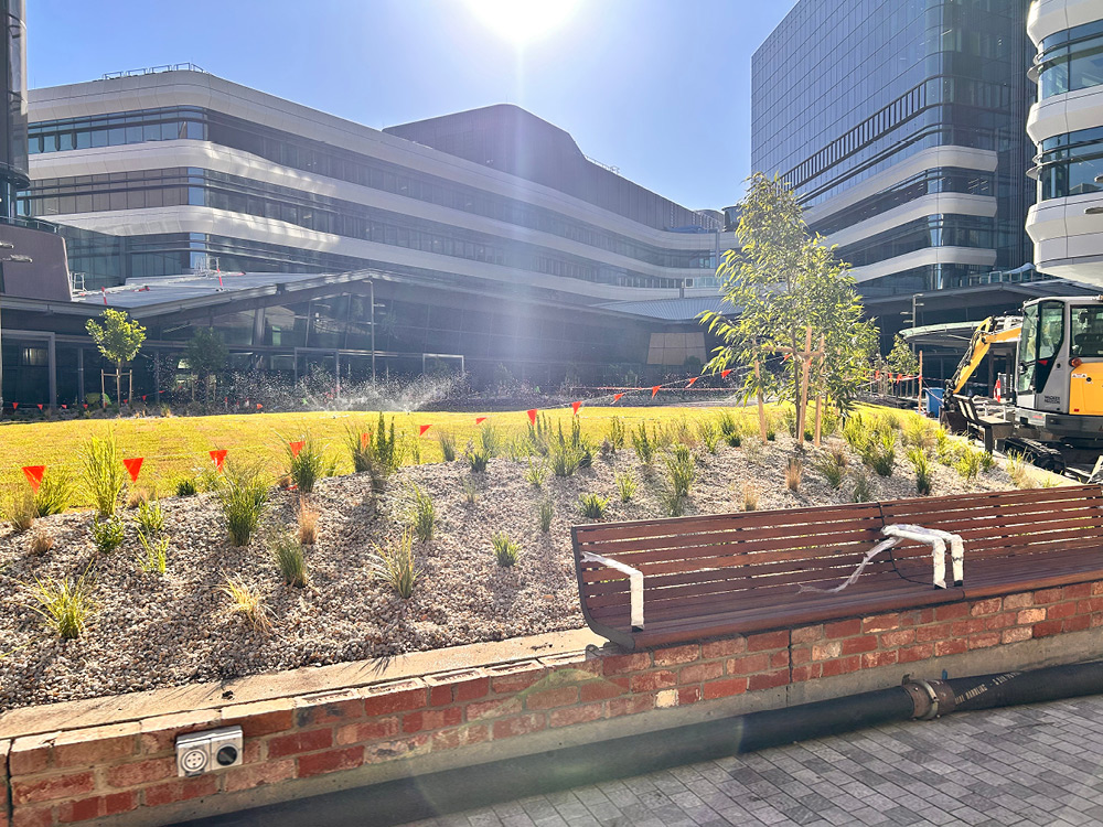 Colourful flowers, grass and a wooden bench create an inviting green space to take a break