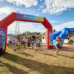 A woman runs triumpant through a finish line followed by a crowd