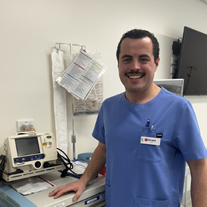 A man wearing blue scrubs, smiling