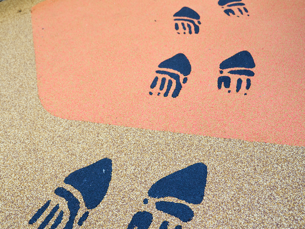 Indigenous footprint motifs incorporated into a coloured play surface in an outdoor courtyard.