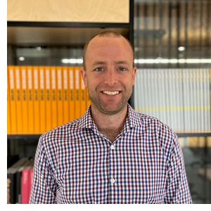 Person standing in front of a bookshelf in an office setting