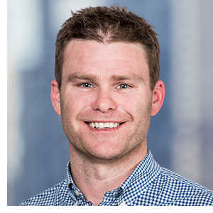 A man in a collared shirt smiles at the camera