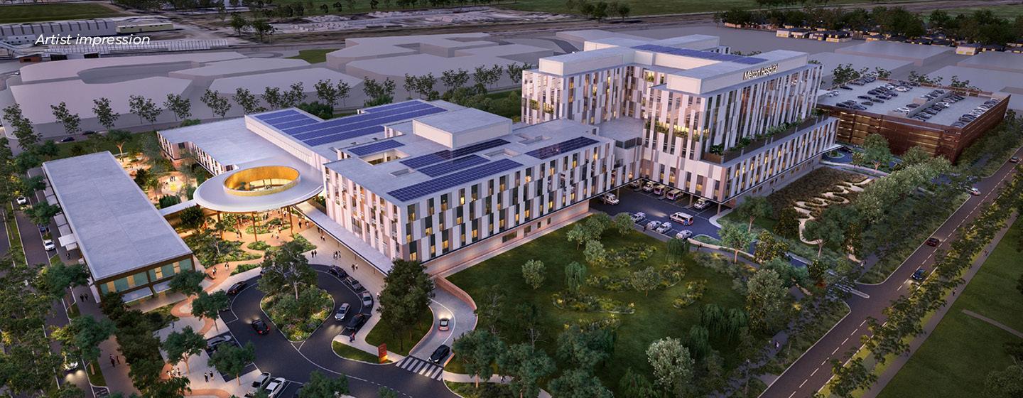 Artist impression of an aerial view of the exterior of the new Melton Hospital, seen in the evening with lighting turned on. Green space surrounds the buildings