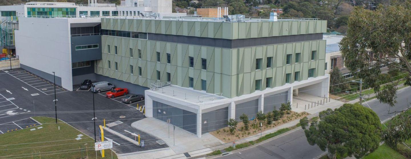 Aerial view of the new Angliss Hospital building, showing the multi-storey exterior, car park and surrounding trees and streets.