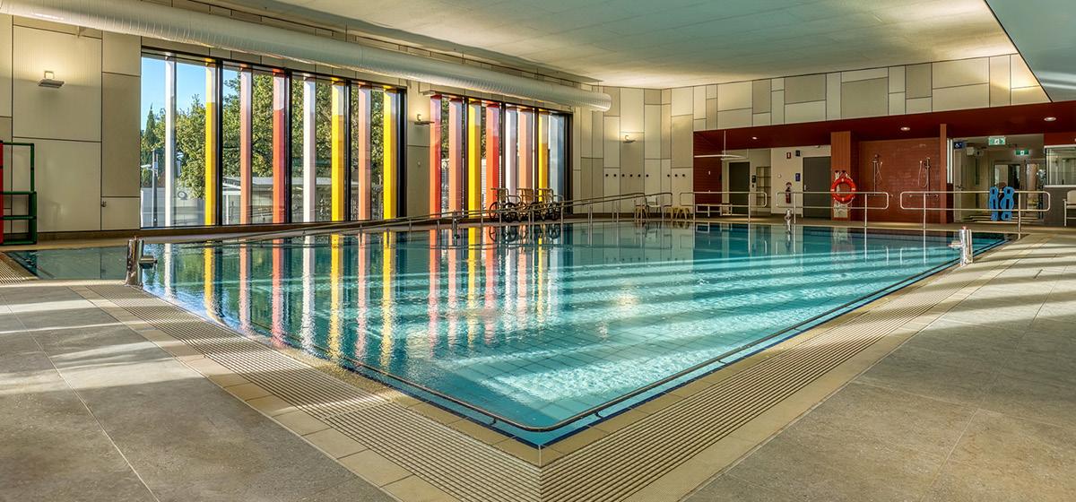 An indoor hydrotherapy pool illuminated by natural light through a multi-coloured window