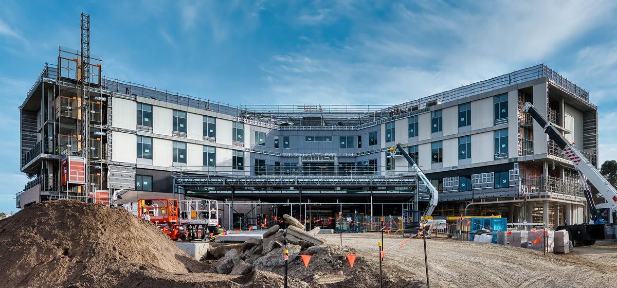 A white building with lots of windows begins to take shape before a blue sky