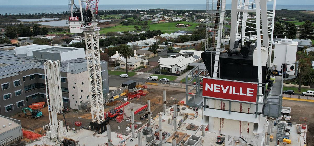 View across the Warrnambool Base Hospital redevelopment construction site showing tower cranes, concrete structures under construction and surrounding residential areas