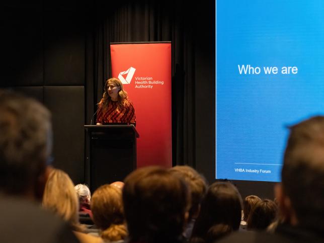 Megan Bourke-O’Neil, CEO of the Victorian Health Building Authority, stands and speaks at a lecturn on a stage