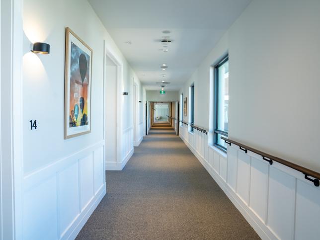 A corridor with white walls and a handrail