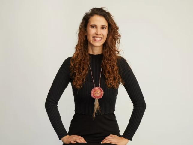A woman stands proudly, hands on hips, smiling at the camera