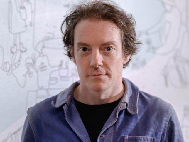 A headshot of a man in a blue shirt