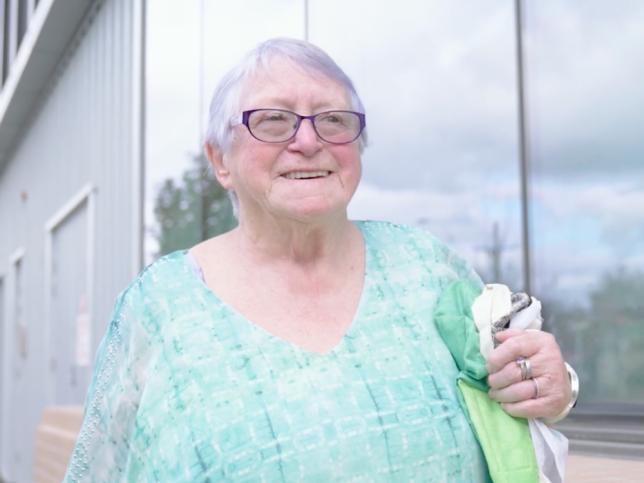 A woman with light purple hair and glasses smiling