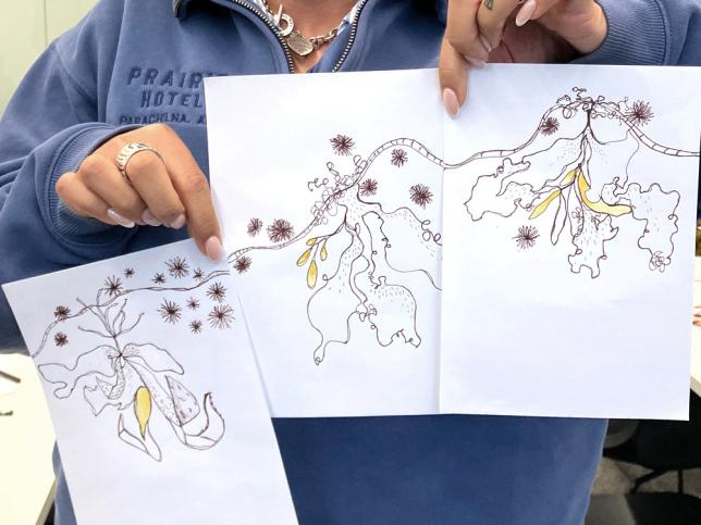 A person holding three pieces of paper which show an interconnected line drawing