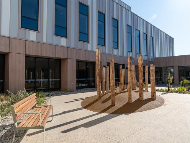 Outdoor area with a log sculpture and timber bench bathed in sunlight