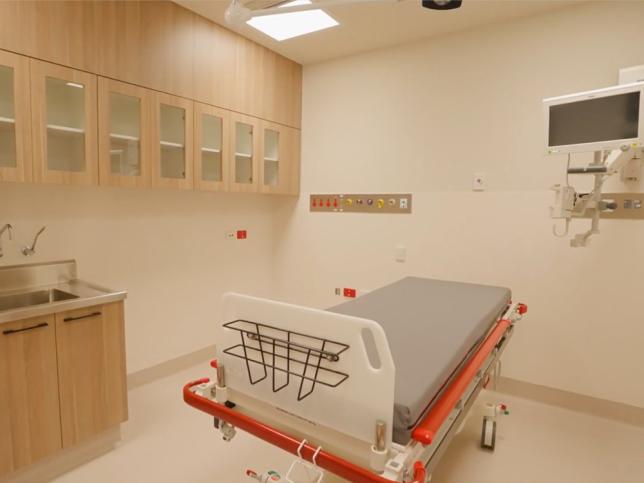 A treatment space with a bed, sink and cupboards