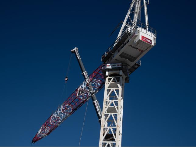 A white tower crane against a blue sky
