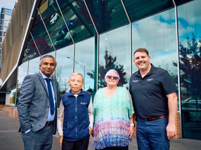 Four people stand smiling infront of a new building