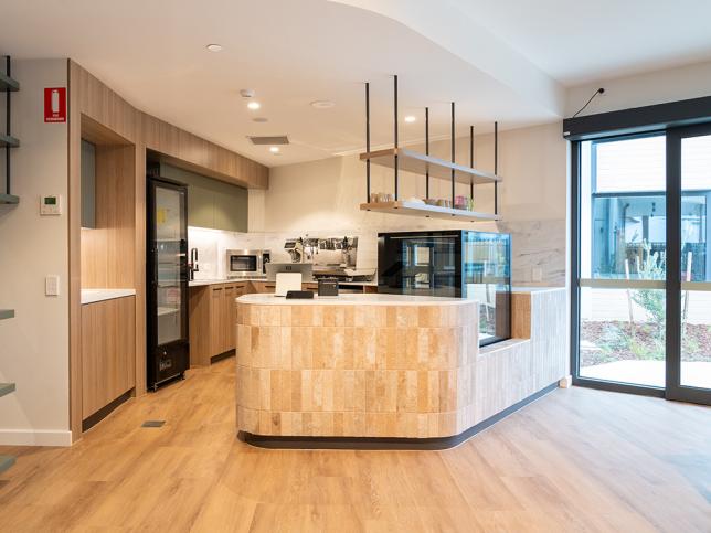 Café area at the new aged care facility, with a kitchen area with appliances and a window in the background.