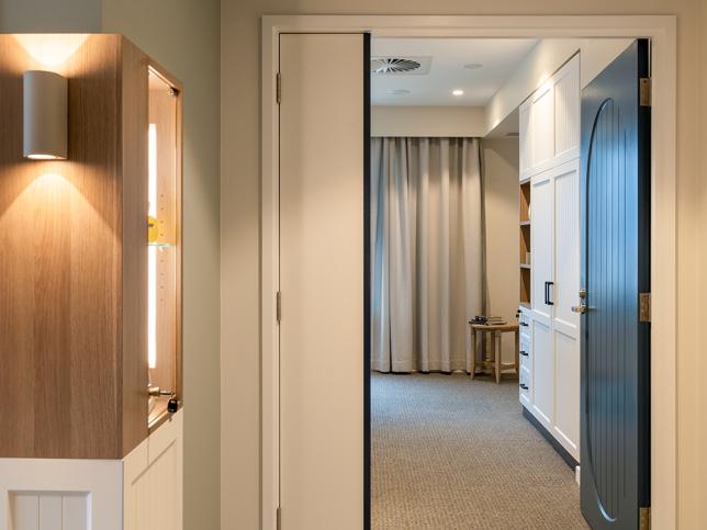 Outside one of the bedrooms with lights in the foreground looking through the door with cupboards in the room.
