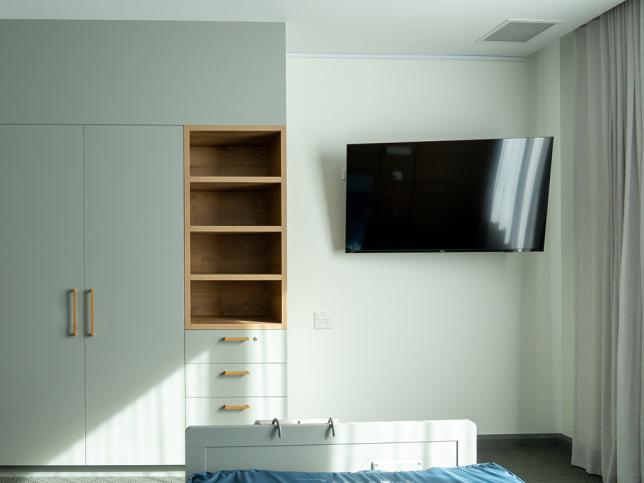 A modern bedroom with lots of storage space and a TV