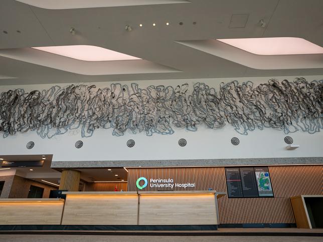 A large horizontal sculptural artwork hangs above a reception area