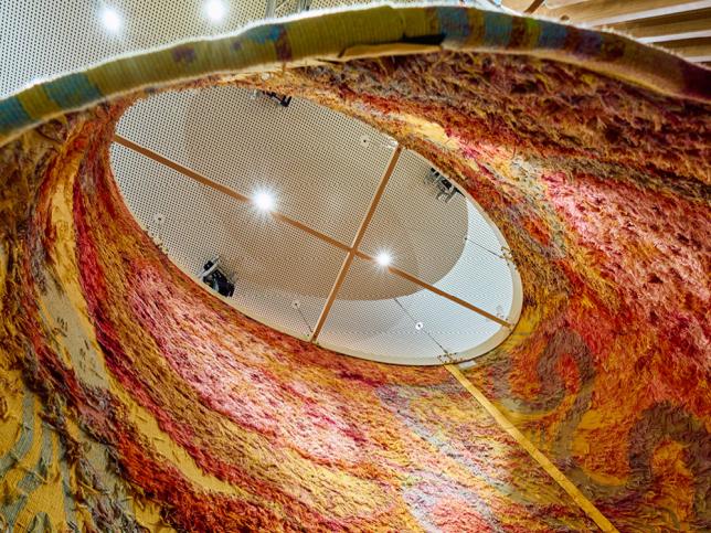 A view from below of a hanging cylindrical tapestry