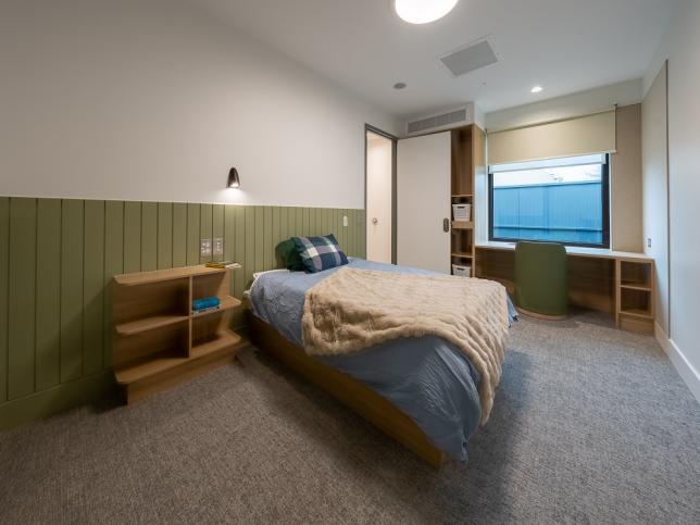 A bedroom with double bed and green panels on the wall