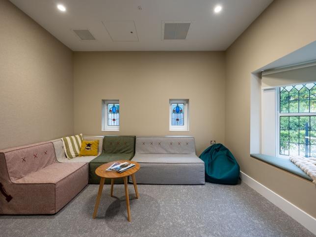 A communal area with coloured couches and leadlight windows