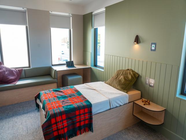 A neat bedroom with a single bed, window seat and desk