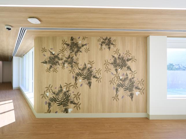 Nature-inspired wall artwork featuring fern leaves and native flora in a hospital corridor.