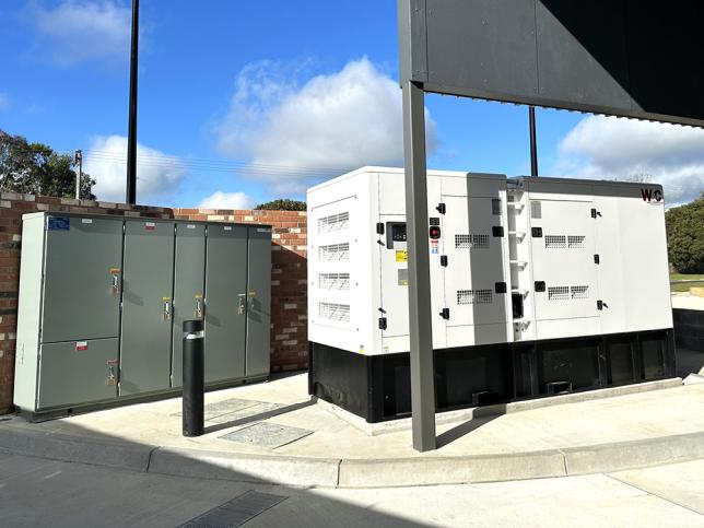 Outdoor electrical cabinets beside a brick wall.