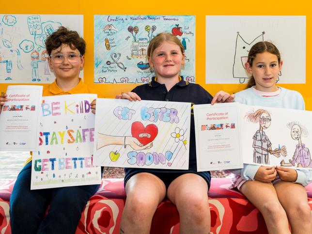 Three children holding artworks