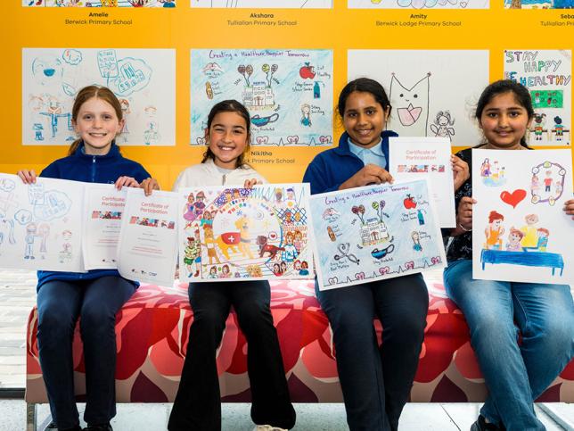 Four children holding up artworks