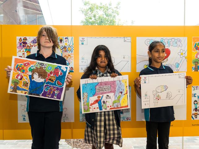Three children holding artworks