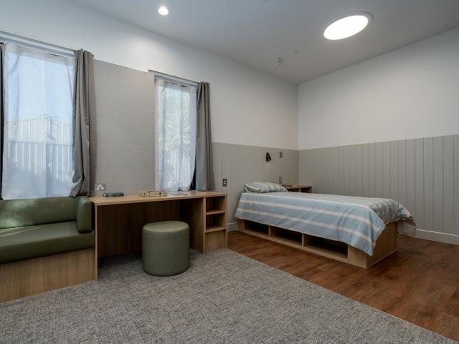 A bedroom with bed, desk and bench seat