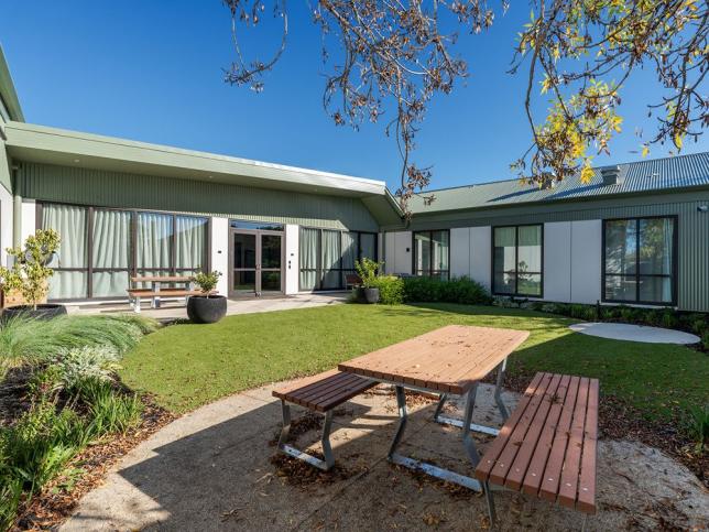 An outdoor space with lawn and picnic bench seating