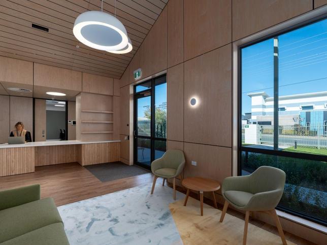 A modern reception area with green chairs and wood panelling