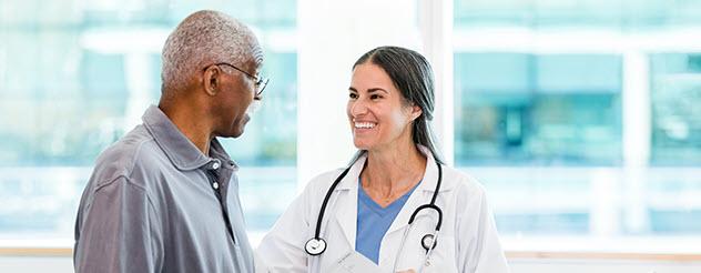 A doctor smiling and talking to a patient in a hospital.