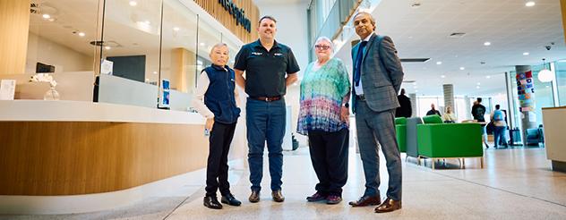 Four people standing next to each other in a hospital reception area