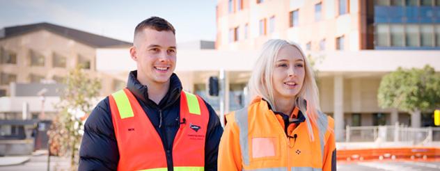 A man and woman in hi-vis smile at the camera