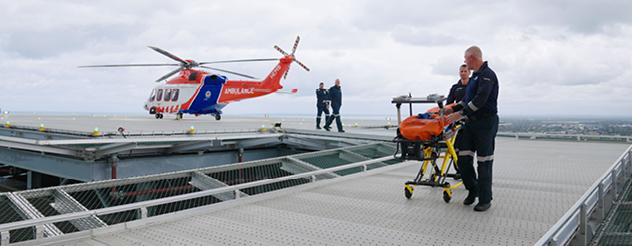 helicopter hovers above rooftop with ambulance stretcher nearby