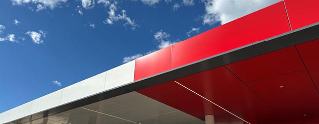 Section of a half red and half white roof with blue sky in the background