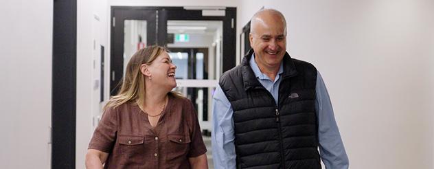 A woman and man walk down the corridor chatting and laughing