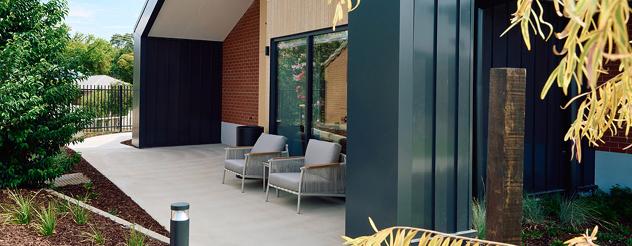 Landscaped outdoor courtyard at a residential aged care home with covered seating, garden beds and accessible walking paths.