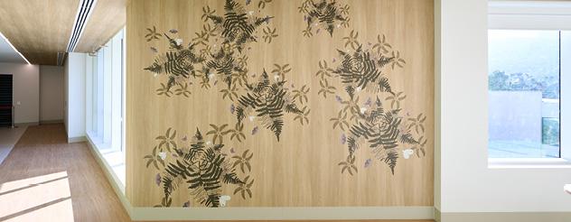 Nature-inspired mural featuring fern leaves, native flora and wildlife imagery in a hospital corridor.