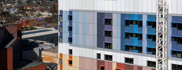 Part of the Ballarat Base Hospital redevelopment building showing colourful exterior cladding and a tower crane during construction.