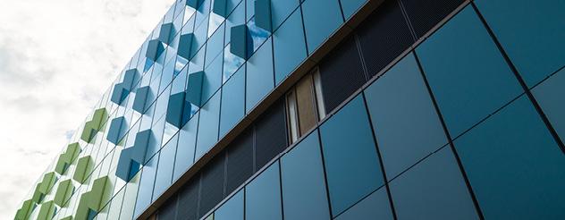 Close-up view of the Barwon Women's and Children's building exterior, showing blue and green glass panels with a diamond pattern against a cloudy sky.